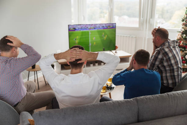 Desperate men watching soccer game on TV and getting nervous
